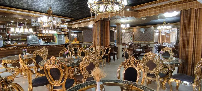 رستوران هتل بوستان با میزهای شیشه‌ای و صندلی‌های طلایی