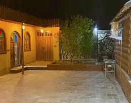 حیاط سنگ‌فرش‌شده کلبه مادر جان در شب