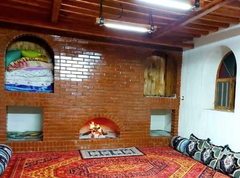 اتاق نشیمن کلبه مادر جان با شومینه آجری و فرش