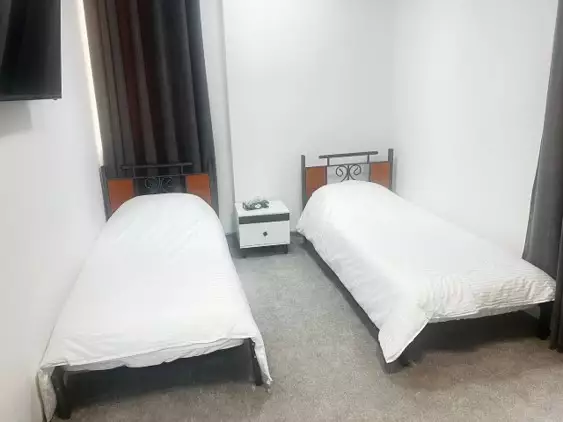 دو تخت یکنفره و میز پاتختی در هتل کوروش