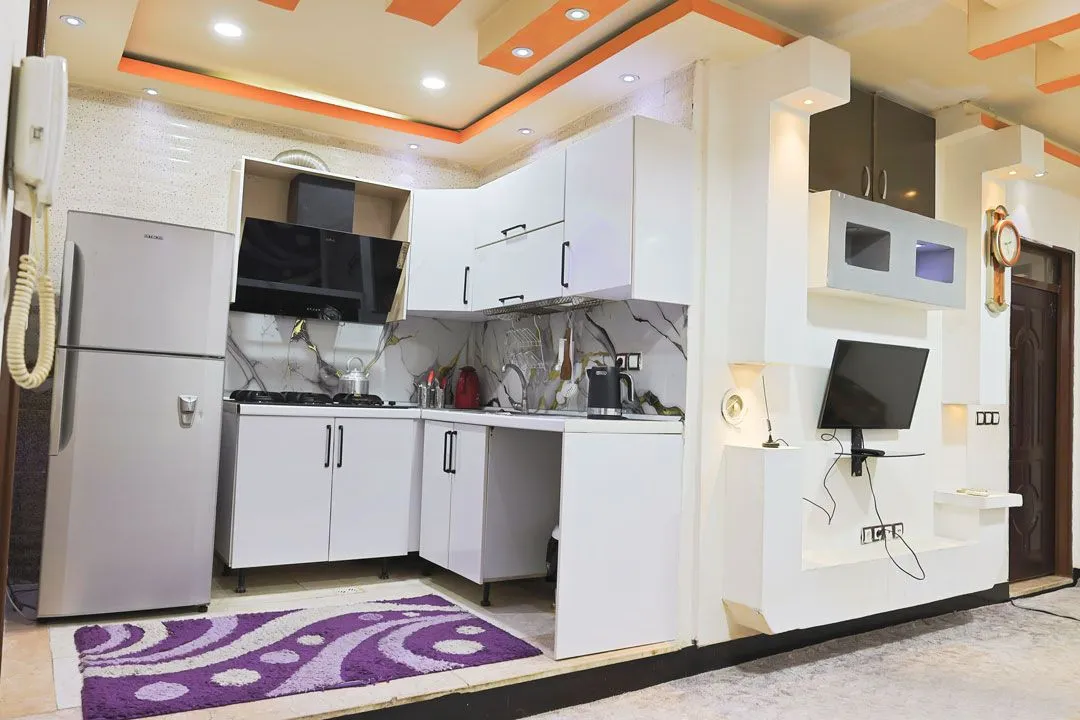 آشپزخانه خلیج فارس با کابینت سفید و تلویزیون