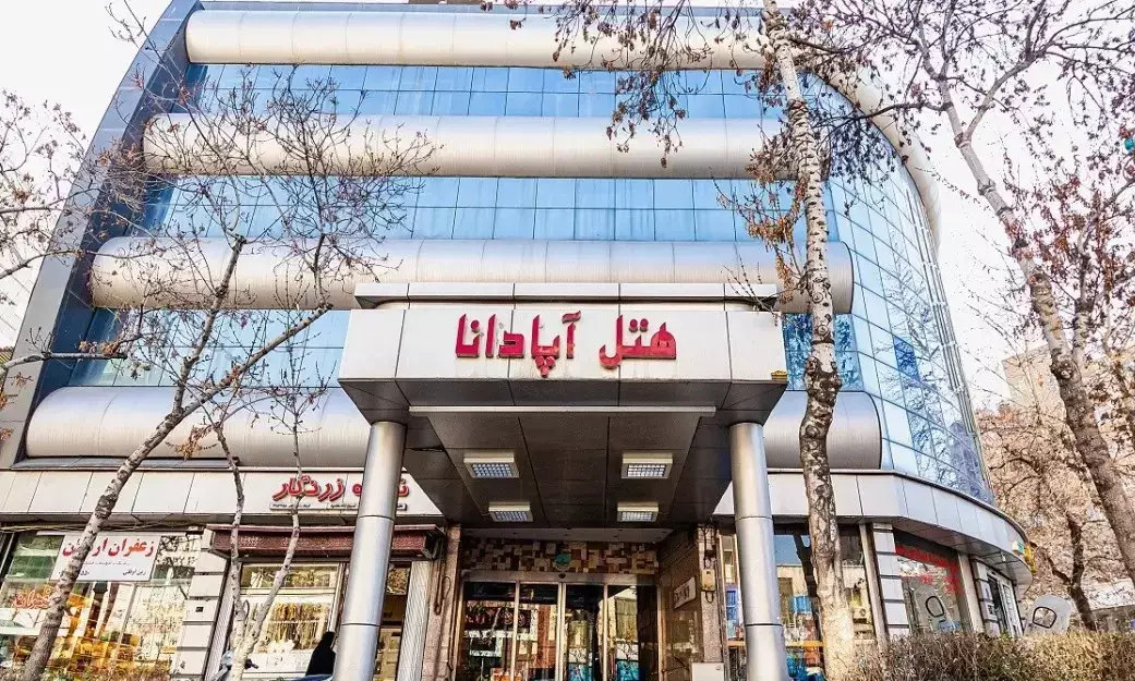ورودی شیشهای هتل آپادانا با تابلوی قرمز
