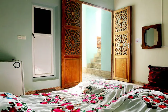اتاق خانه عروسک با تخت گل‌دار و درهای چوبی مشبک