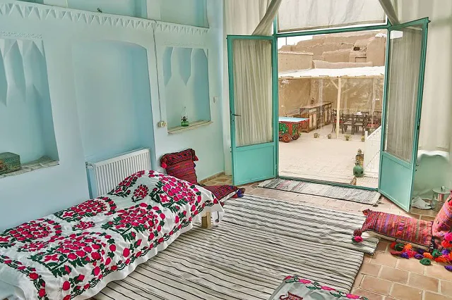 اتاق خانه عروسک با رختخواب‌های گلدار و در باز به حیاط