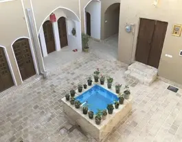 حیاط سنتی هتل رویای کویر با حوض و گلدان‌های گل