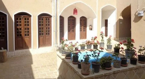 حوض آبی حیاط هتل رویای کویر میان گلدان‌های گل