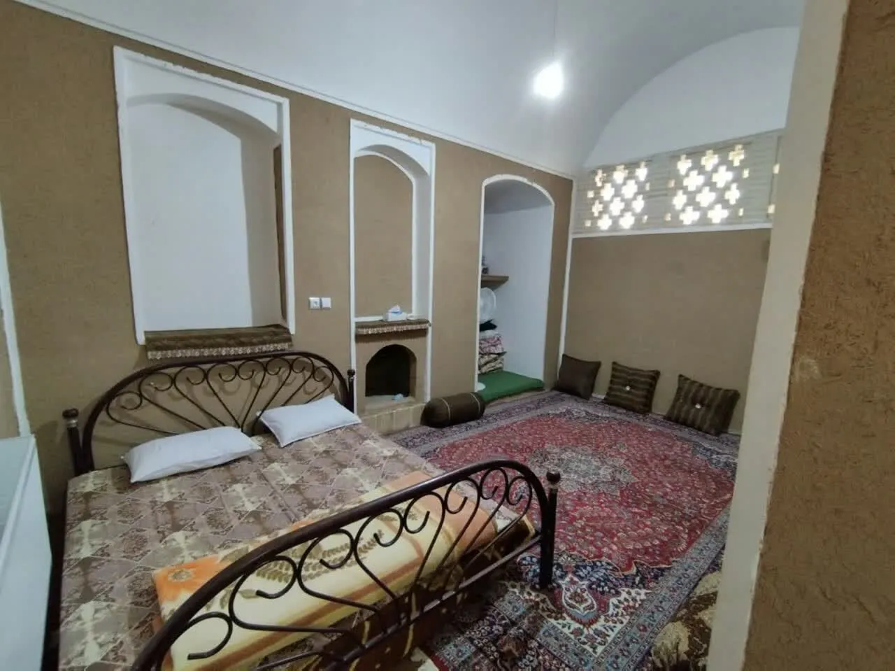 اتاق عمارت شاباز با تخت فلزی و فرش ایرانی