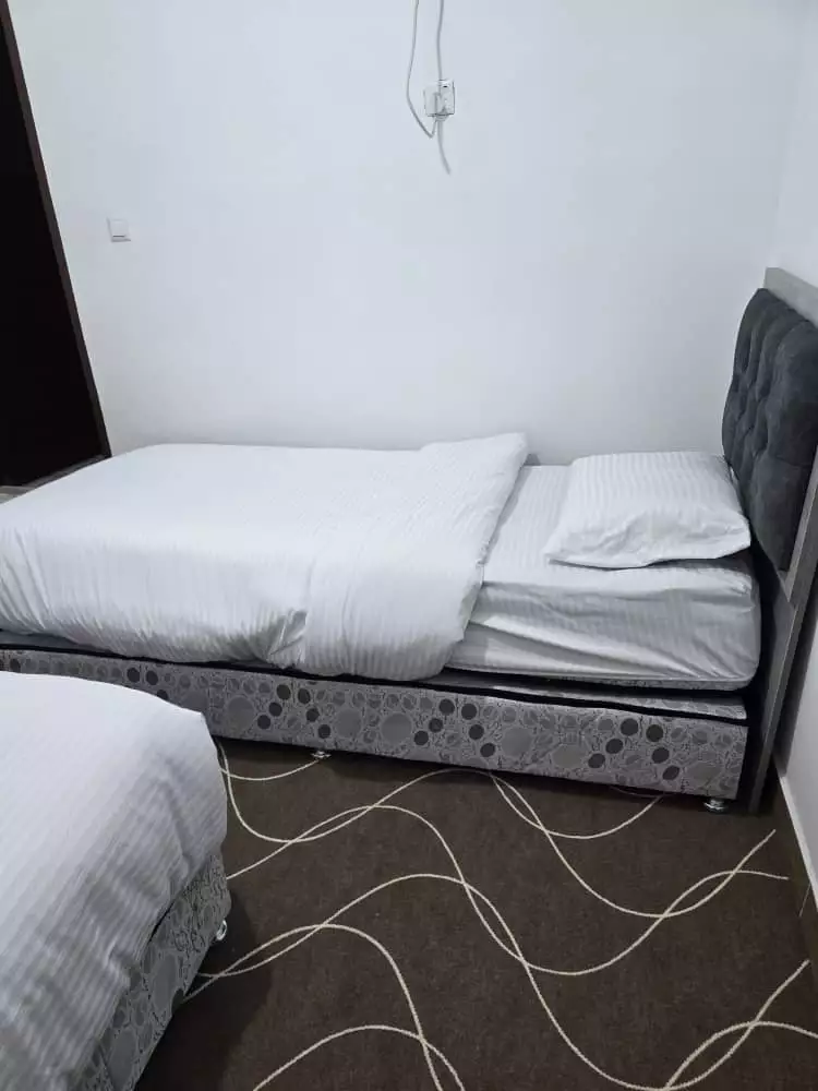 تخت یک‌نفره با تاج خاکستری و ملحفه سفید هتل دریا
