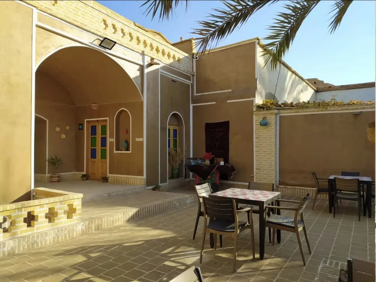 حیاط عمارت شاطر با میزهای غذاخوری و ایوان