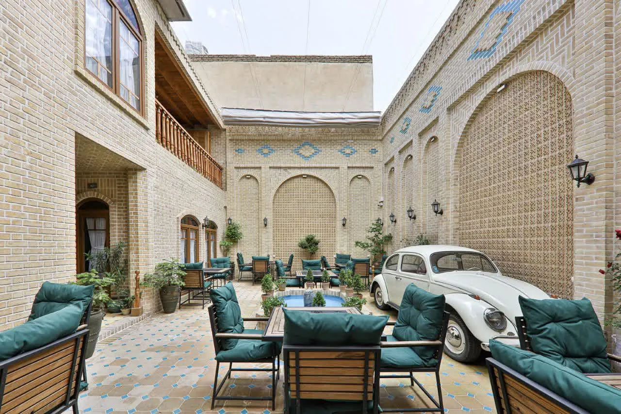 حیاط هتل جیران با میزهای فضای باز و خودروی کلاسیک
