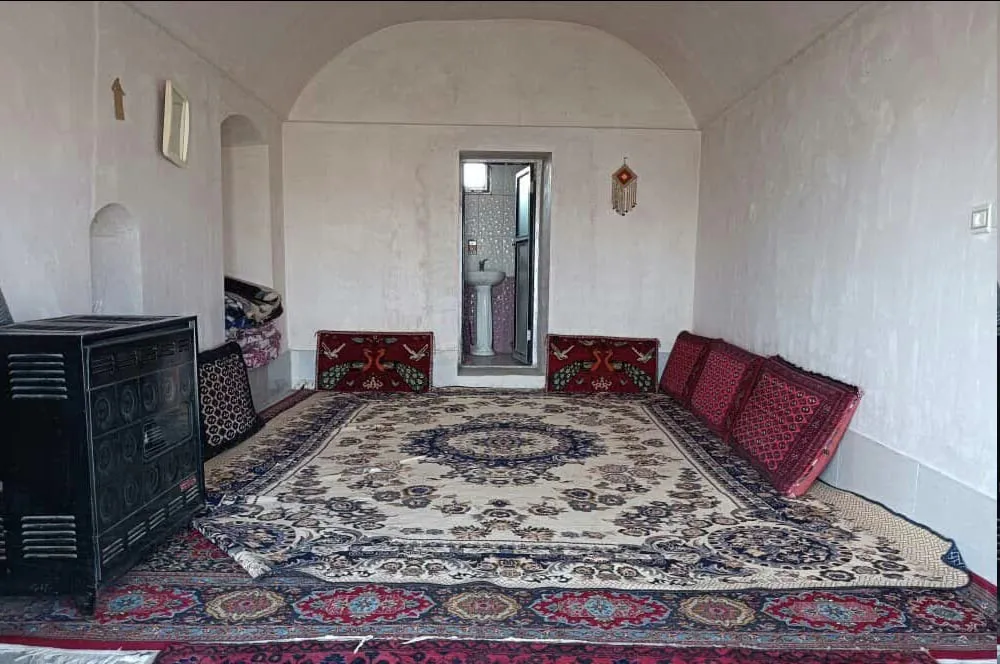 اتاق زرین چاه با فرش ایرانی و بخاری فلزی