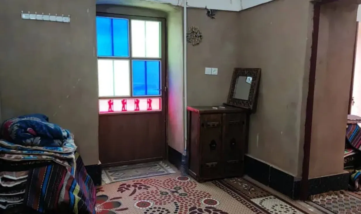 اتاق اقامتگاه بابا حاجی حلوان با پنجره رنگی و فرش