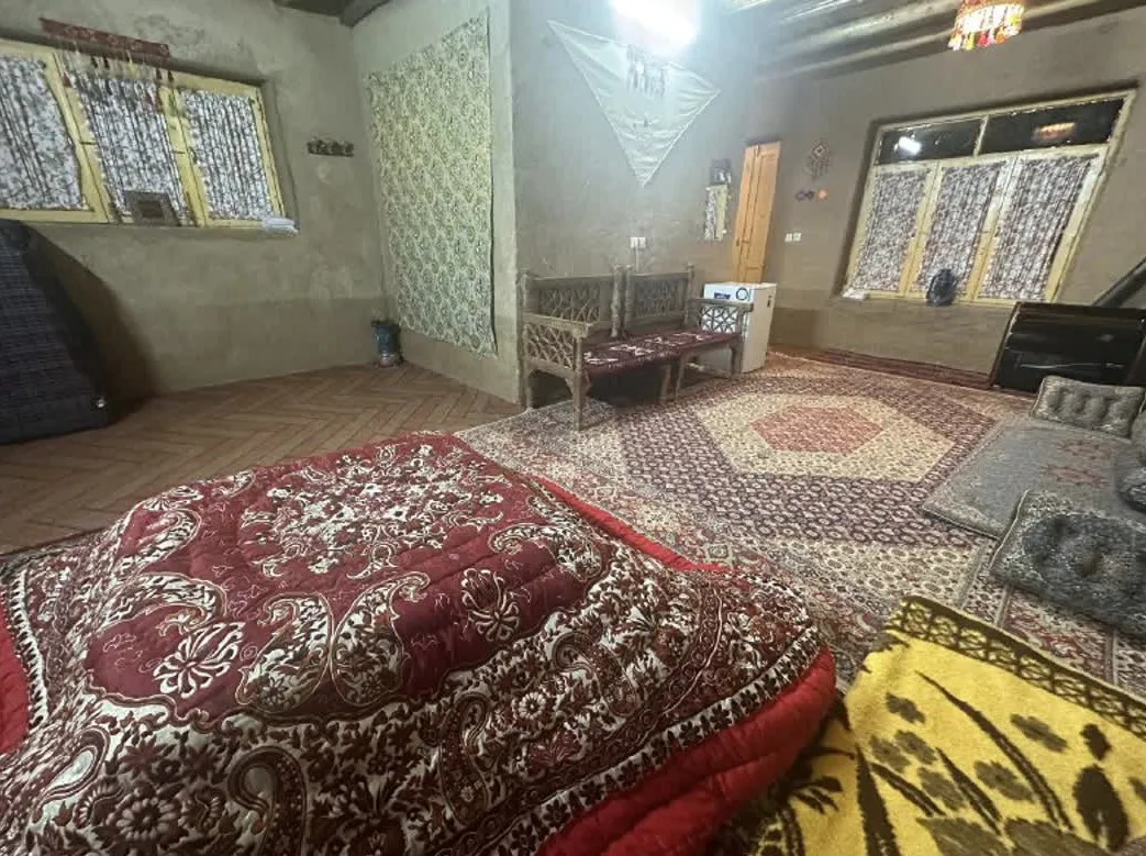 اتاق اقامتگاه دره خورشید با رختخواب سنتی و فرش‌های ایرانی