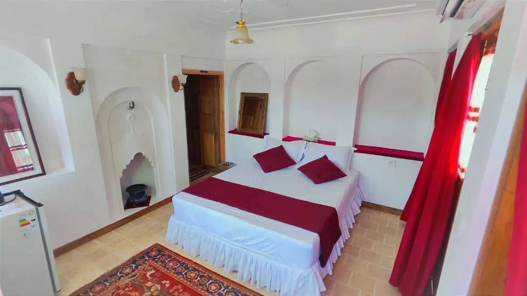 اتاق با تخت دونفره زرشکی در عمارت تاریخی دلگشا