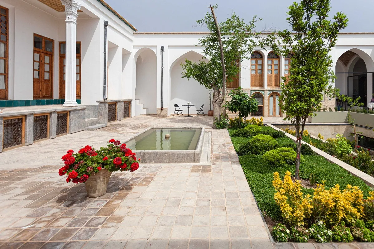 حیاط سنتی هتل درختی با حوض و باغچه