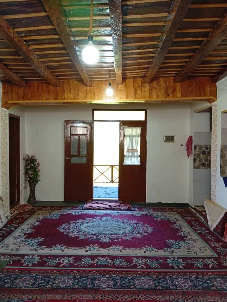 اتاق نشیمن بوم سبز هیرکانی با سقف چوبی و فرش ایرانی