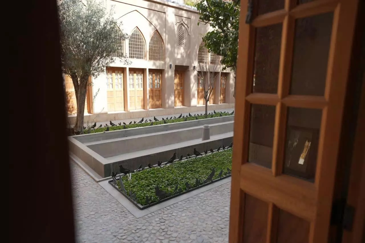 حیاط هتل استادی با حوض و درختان