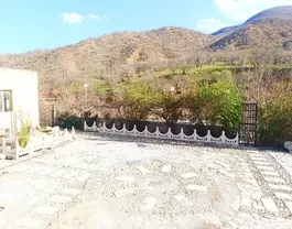 محوطه سنگ‌فرش اقامتگاه تنگ بهرام با چشم‌انداز کوهستان