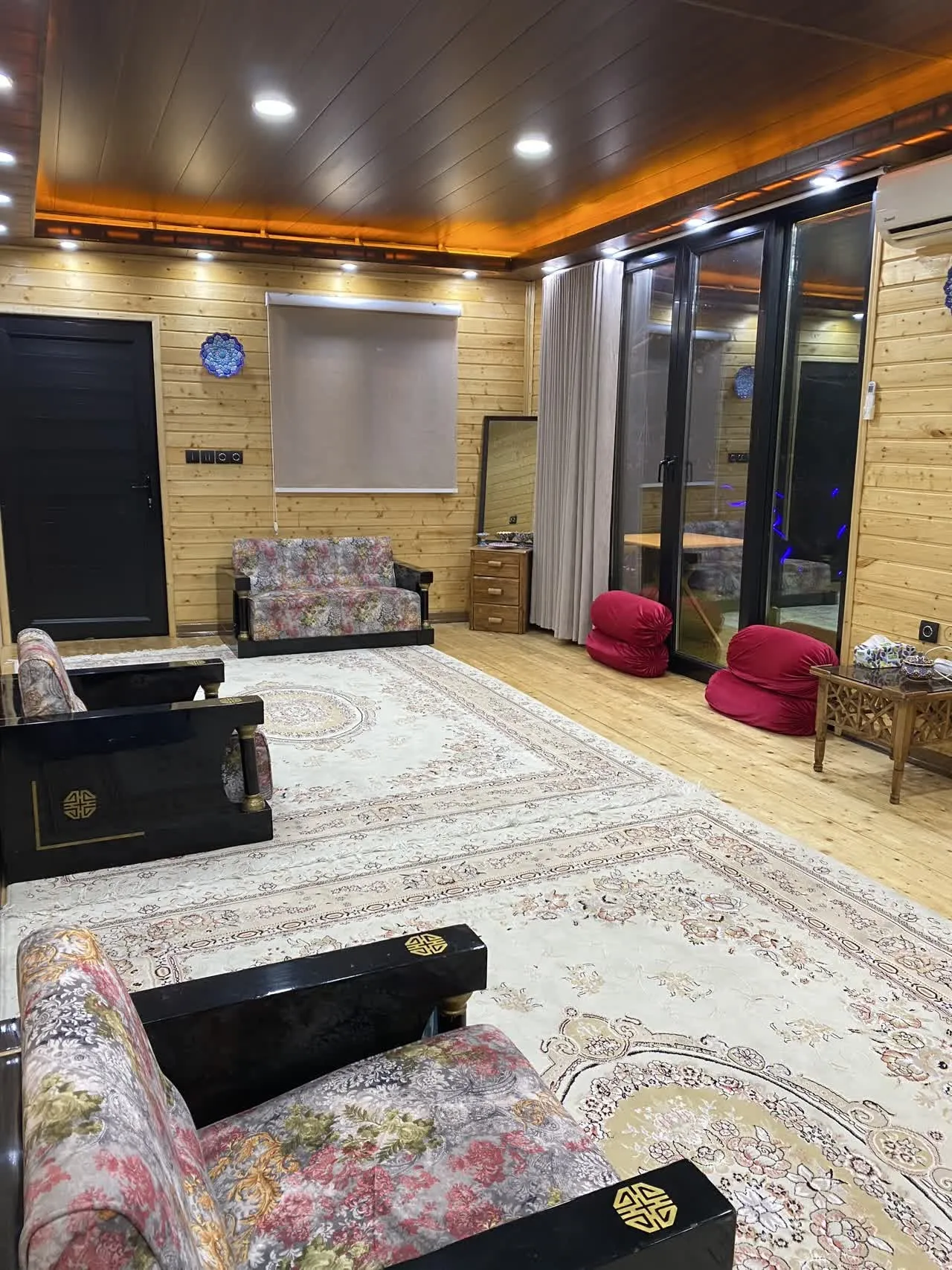 نشیمن چوبی تاج محل تیرتاش با فرش و مبل‌های طرح‌دار