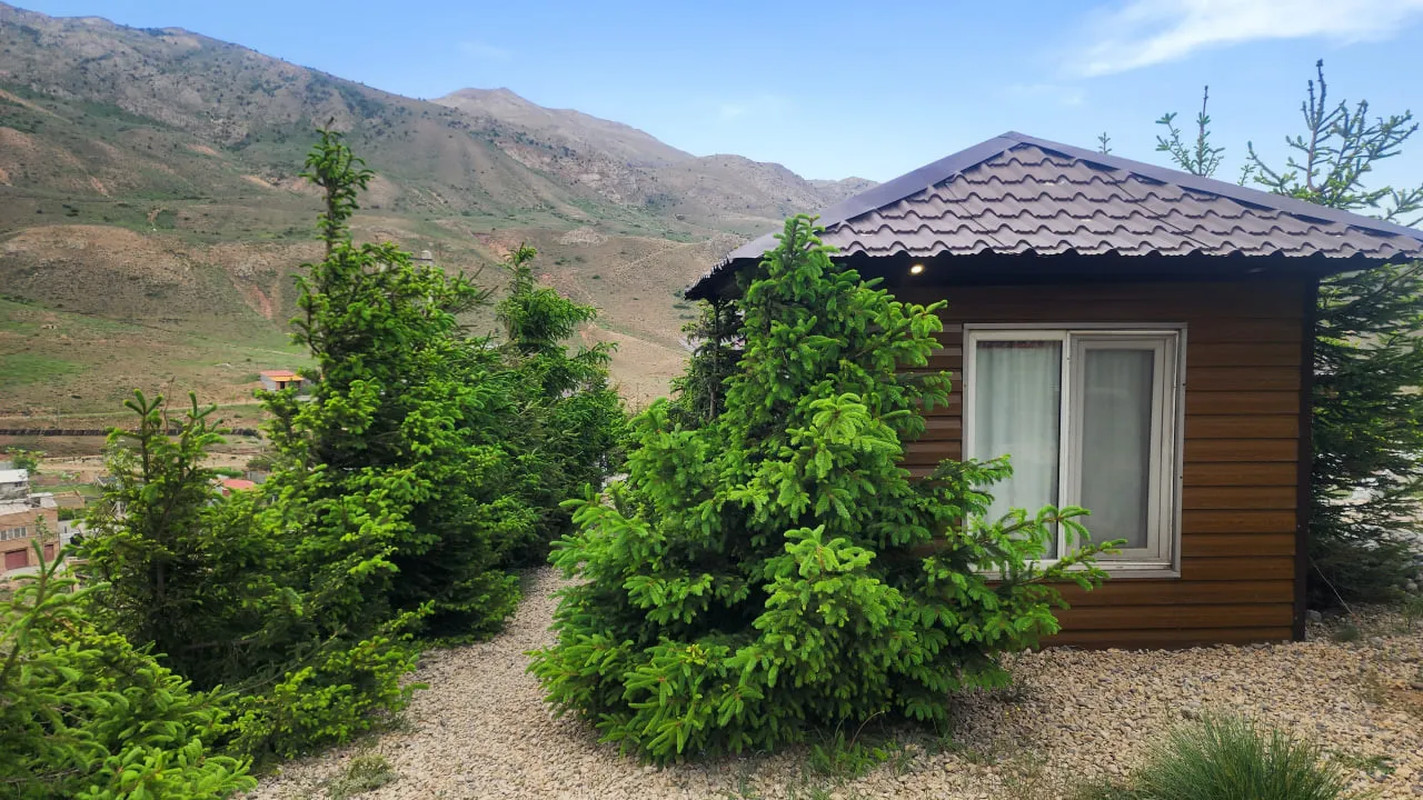 کلبه چوبی میان درختان و کوهستان هتل آرش کمانگیر