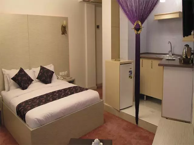 تخت دونفره و آشپزخانه کوچک اتاق هتل نگین