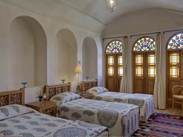 اتاق منوچهری با تخت‌های یک‌نفره و پنجره‌های رنگی