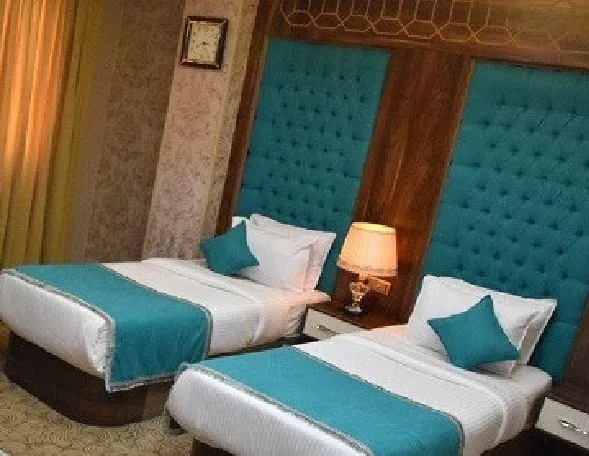 دو تخت یک‌نفره با روتختی فیروزه‌ای در هتل آریا