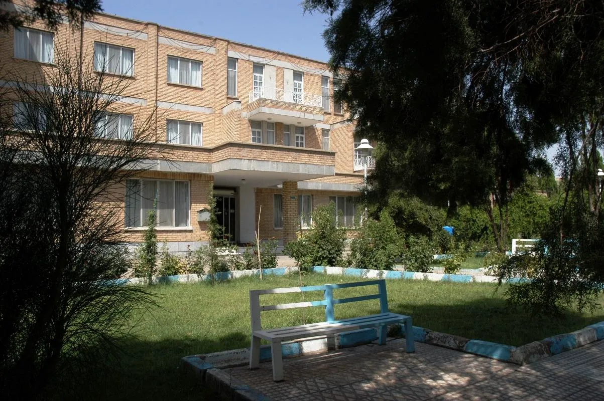 نمای ساختمان آجری هتل جهانگردی در میان فضای سبز
