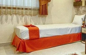 تخت یک‌نفره با روتختی نارنجی در هتل سامرا