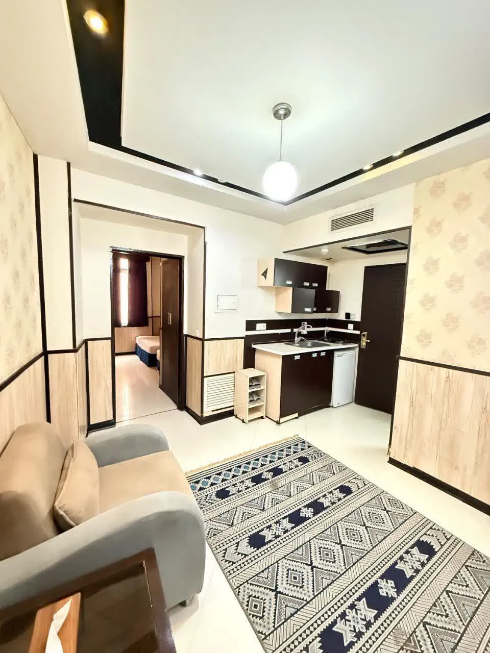 نشیمن هتل دیدار با فرش هندسی و آشپزخانه