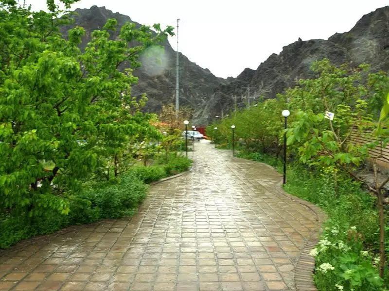 مسیر سنگ‌فرش‌شده میان فضای سبز هتل بزرگ کوهستان