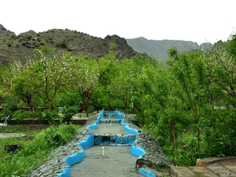 جوی آب آبی میان درختان و کوهستان هتل بزرگ کوهستان