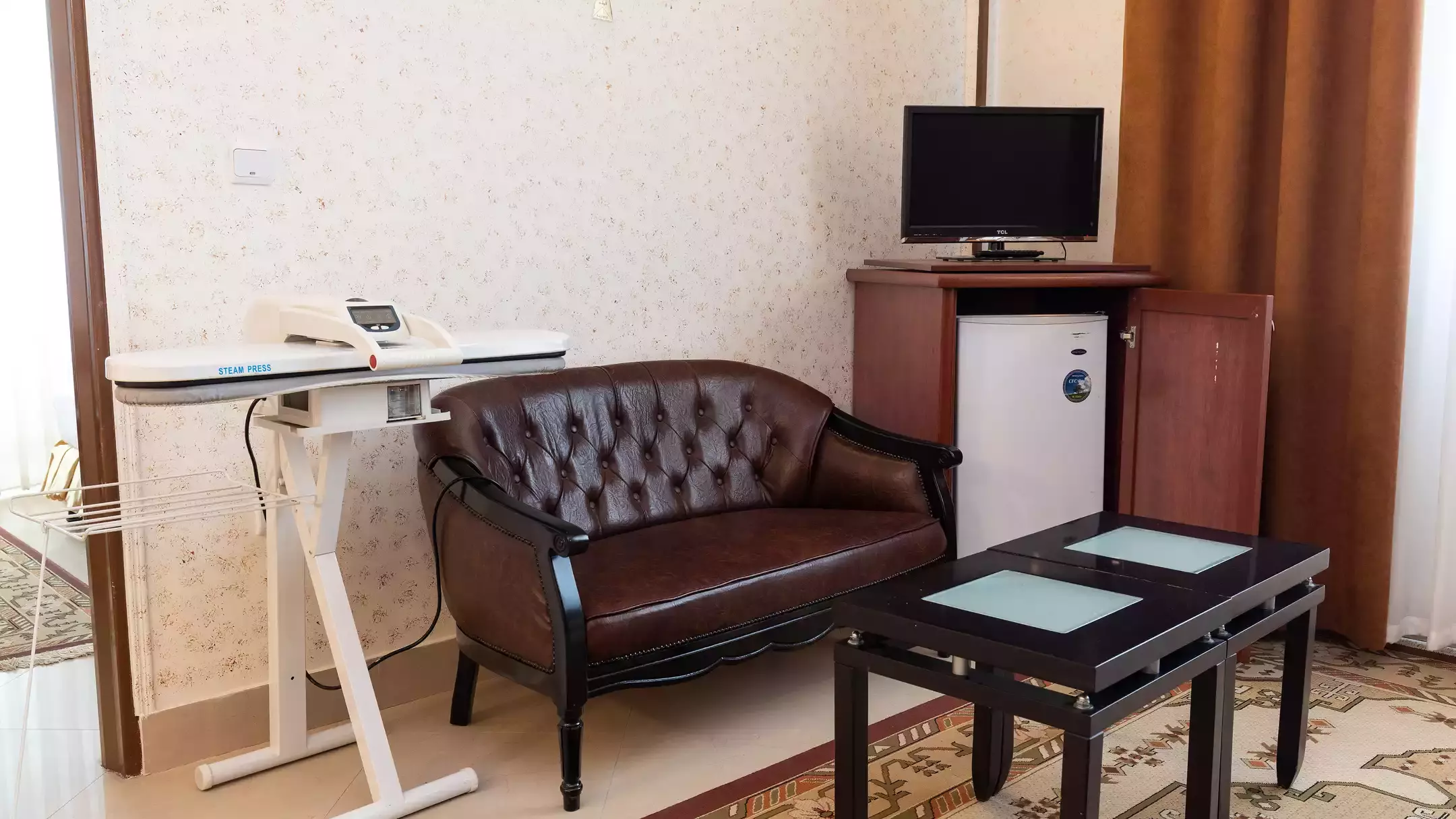 مبل چرمی و میز تلویزیون در اتاق هتل هلیا