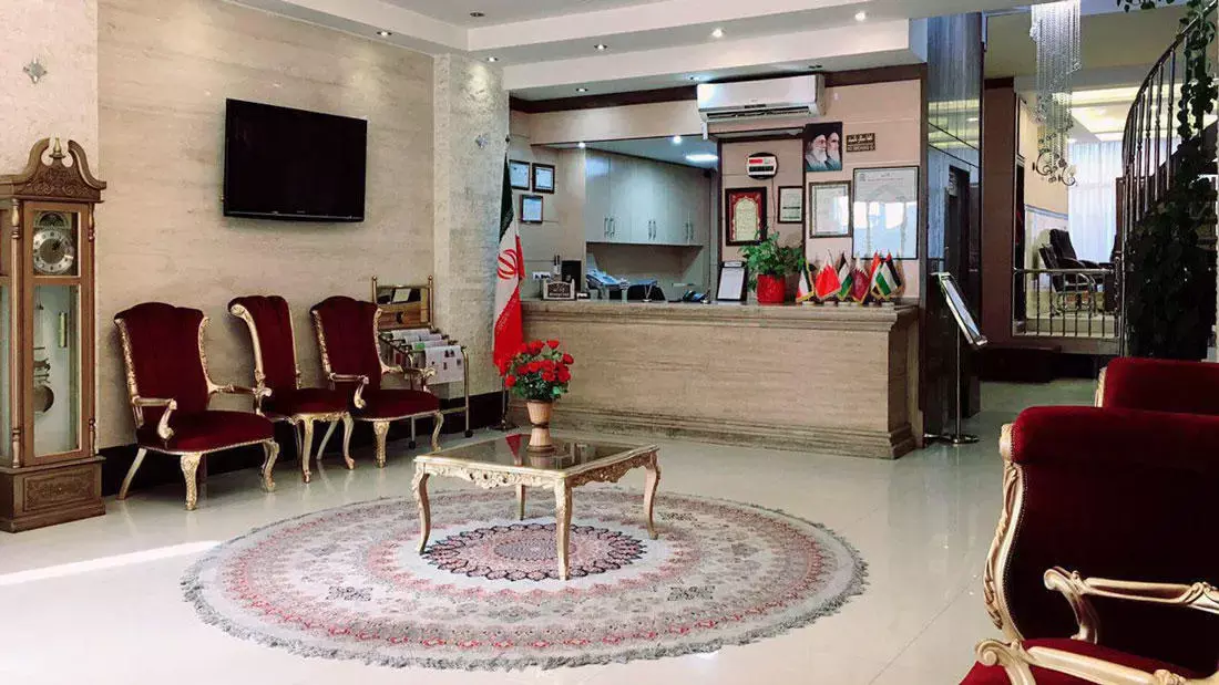 پذیرش هتل معین درباری با مبلمان قرمز و میز چوبی