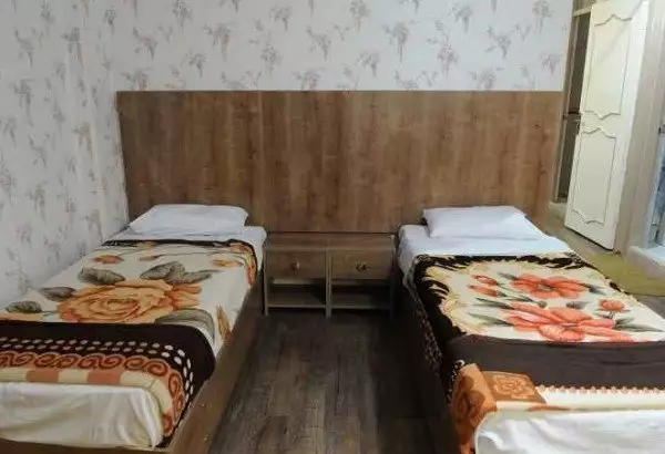 دو تخت یک‌نفره با روتختی گل‌دار در هتل هدیه
