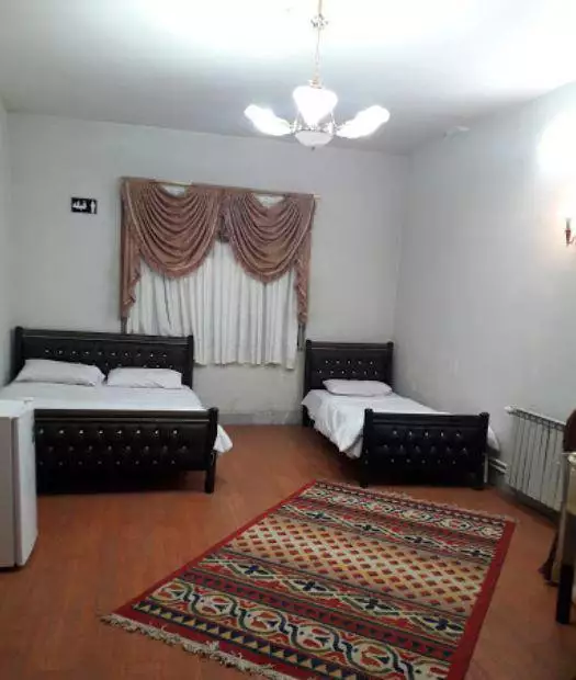 اتاق سهتخته هتل کهکشان با فرش سنتی و تختهای تیره