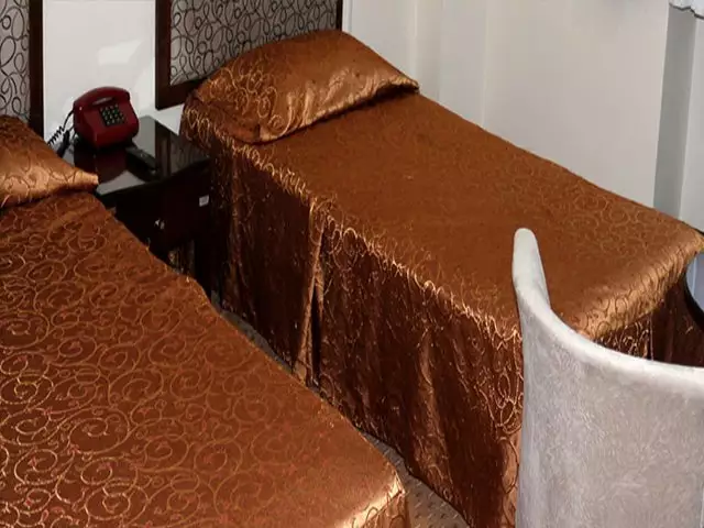 دو تخت یکنفره با روتختی قهوهای در هتل گاجره