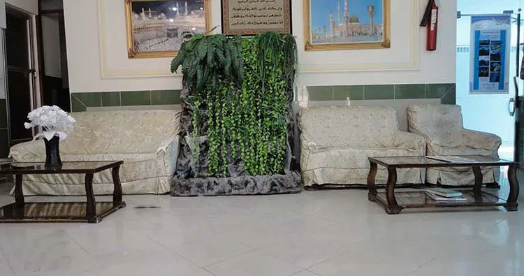 نشیمن هتل قائم با مبل‌های کرم و آب‌نمای گیاهی