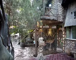 ورودی سنگی با چهره کنده‌کاری‌شده در میان درختان