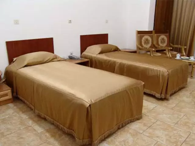 دو تخت یک‌نفره با روتختی قهوه‌ای در هتل بهجت