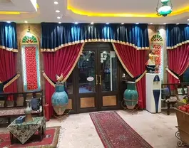 ورودی هتل ابیانه با پرده‌های قرمز و گلدان‌های فیروزه‌ای