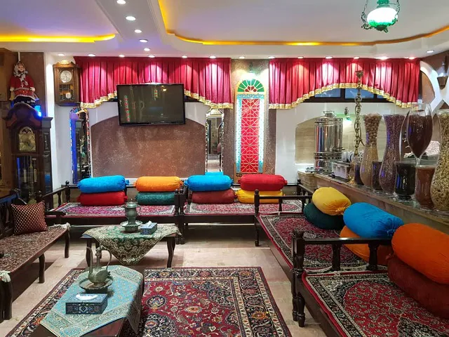 نشیمن هتل ابیانه با پشتی‌های رنگارنگ و فرش ایرانی