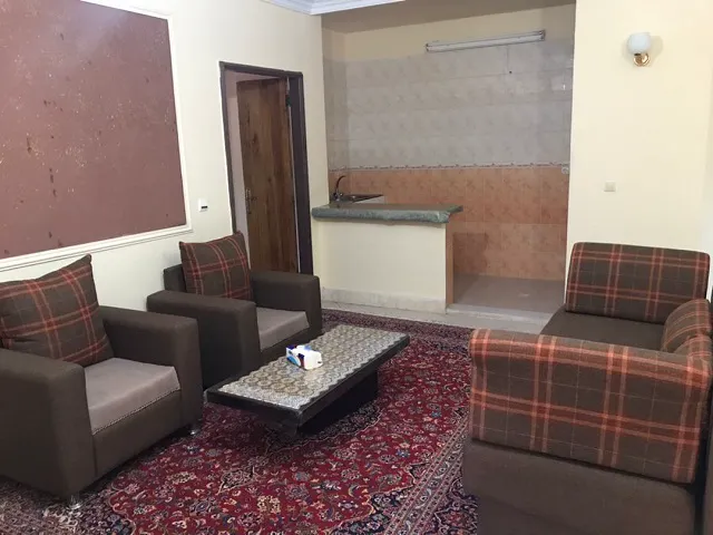 نشیمن هتل ابیانه با مبل‌های چهارخانه و فرش قرمز
