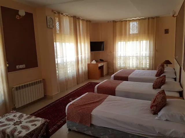 اتاق سه‌تخته هتل ابیانه با پنجره‌های بلند و پرده روشن