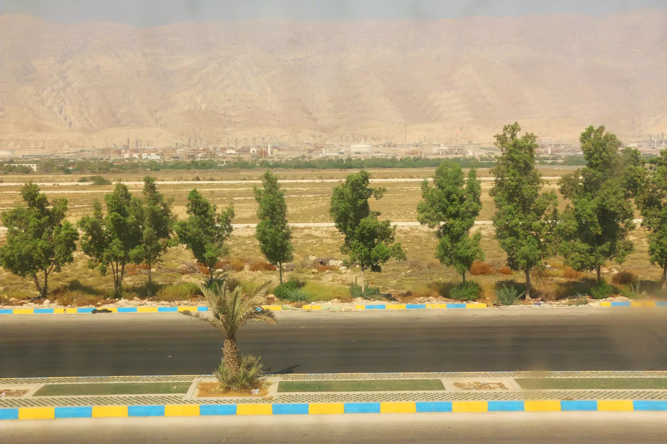 درختان کنار جاده با کوهستان در پس‌زمینه هتل رمیله