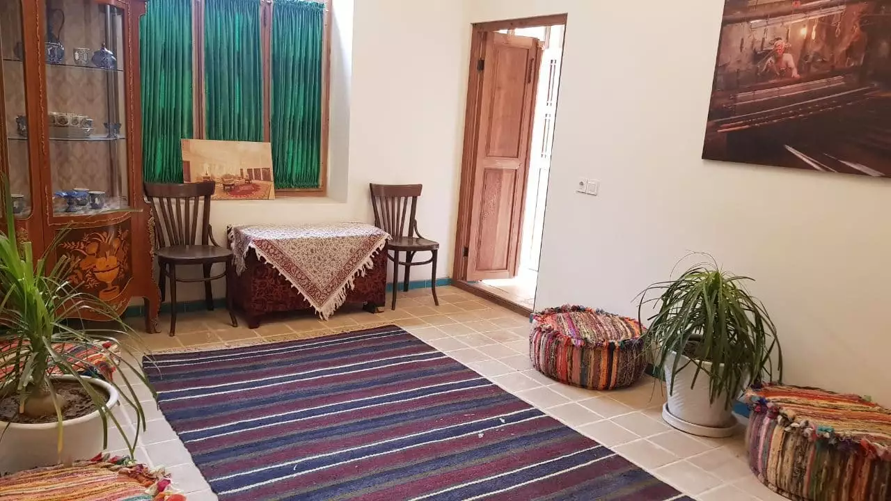فضای نشیمن مهینستان راهب با فرش راهراه و صندلی چوبی
