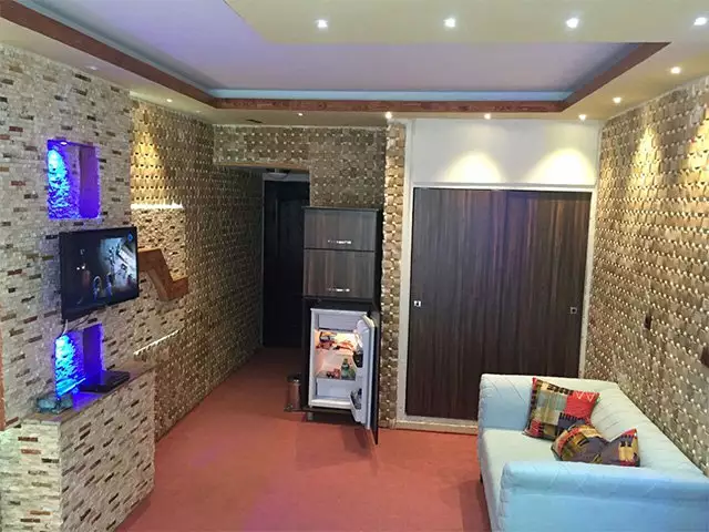 فضای نشیمن جهانگردی چلندر با یخچال کوچک و مبل