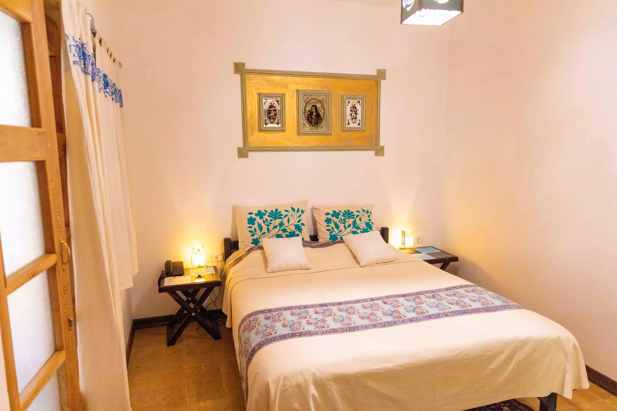 تخت دونفره با کوسن‌های فیروزه‌ای در هتل بخردی