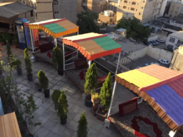 سایه‌بان‌های رنگی و فضای نشیمن حیاط هتل شارستان
