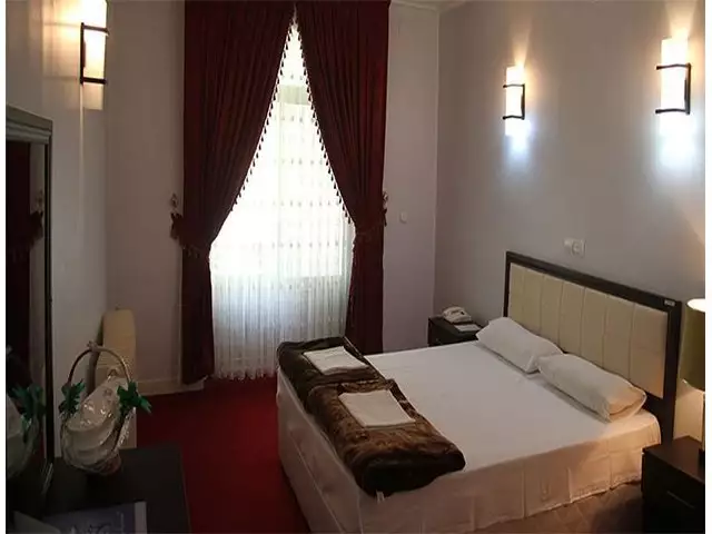 اتاق هتل جهانگردی با تخت دونفره و پرده زرشکی